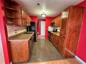 Kitchen featuring decorative backsplash, a textured ceiling, stainless steel appliances, sink, and wood-type flooring