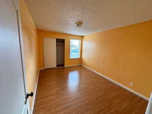 Unfurnished bedroom featuring a textured ceiling, hardwood / wood-style flooring, and a closet