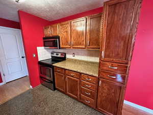 Kitchen featuring decorative backsplash, dark hardwood / wood-style flooring, a textured ceiling, and appliances with stainless steel finishes