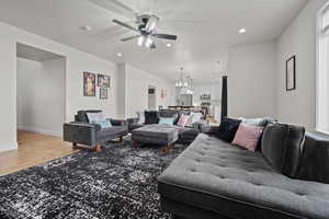 Living room with hardwood / wood-style flooring and ceiling fan with notable chandelier