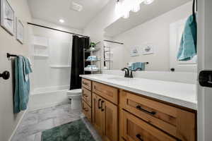 Full bathroom with shower / bathtub combination with curtain, vanity, and toilet