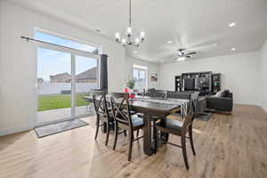 Dining space with ceiling fan with notable chandelier and light wood-type flooring