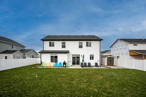 Rear view of house with a patio area, a yard, and a storage shed