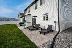 Back of property with a patio area, a mountain view, and a yard