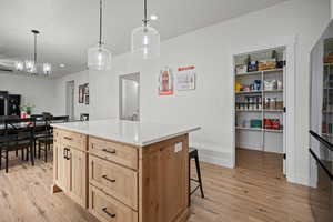 Kitchen featuring light brown cabinets, decorative light fixtures, light hardwood / wood-style flooring, a notable chandelier, and a kitchen island