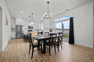 Dining space featuring light hardwood / wood-style floors, sink, and a chandelier