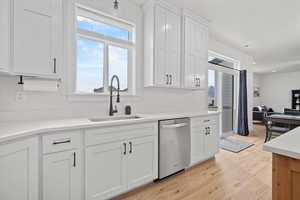 Kitchen featuring white cabinets, dishwasher, light wood-type flooring, and sink