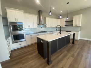 Kitchen featuring white cabinets, wall chimney exhaust hood, dark hardwood / wood-style floors, and appliances with stainless steel finishes