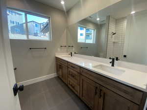 Bathroom with tile patterned floors, vanity, tiled shower, and toilet