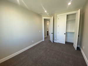 Unfurnished bedroom featuring dark carpet and a closet