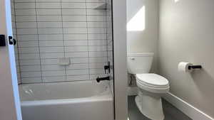 Bathroom with tile patterned floors, tiled shower / bath combo, and toilet