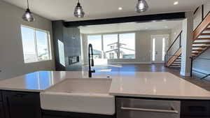 Kitchen featuring a wealth of natural light, dark wood-type flooring, stainless steel dishwasher, and decorative light fixtures