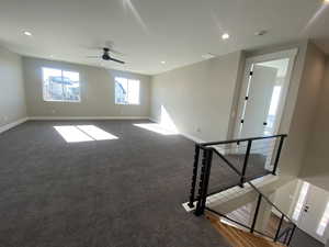 Unfurnished room featuring dark colored carpet and ceiling fan