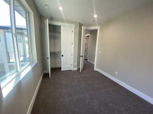 Unfurnished bedroom with dark colored carpet and a closet