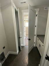 Interior space featuring electric dryer hookup, cabinets, and dark tile patterned floors