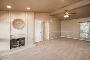 Master bedroom with ceiling fan, lofted ceiling with beams, carpeted floors, and a fireplace