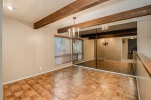 Dining area featuring parquet floors, beam ceiling.