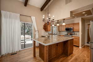 Kitchen featuring wood flooring, appliances with stainless steel finishes, beam ceiling, kitchen peninsula/breakfast bar.