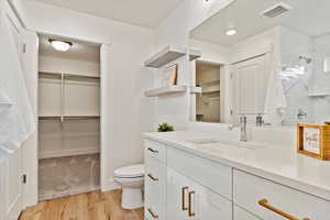 Bathroom featuring vanity, toilet, a shower, and wood-type flooring