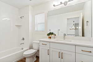 Full bathroom featuring an inviting chandelier, tub / shower combination, toilet, vanity, and hardwood / wood-style flooring