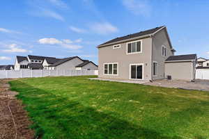 Back of house with a patio and a lawn