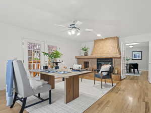 Office area with ceiling fan, light hardwood flooring, a fireplace, and french doors