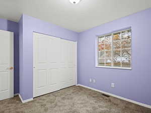 Bedroom #3 with a textured ceiling, light carpet, and a closet