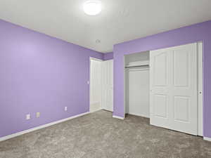 Bedroom #4 with light colored carpet, a textured ceiling, and a closet