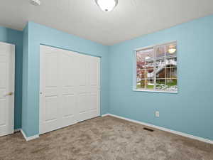 Bedroom #2 with a textured ceiling, light carpet, and a closet