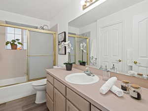 Full bathroom #3 with combined bath/shower with glass door, hardwood / wood-style floors, vanity, and toilet