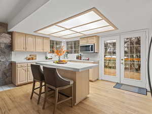 Kitchen with backsplash, a kitchen island, light hardwood flooring, and a breakfast bar area