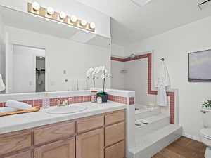 Primary bathroom with backsplash, a soaker tub/shower, vanity, and toilet