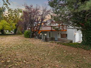 Exterior space with a garage and a wooden deck and a covered patio with entrance to lower level.