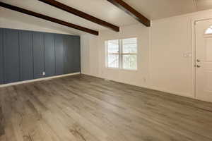 Interior space featuring vaulted ceiling with beams and light hardwood / wood-style floors