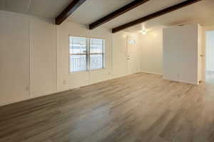 Spare room with light hardwood / wood-style flooring and lofted ceiling with beams