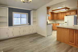 Kitchen featuring sink, a notable chandelier, lofted ceiling, white appliances, and light wood-type flooring