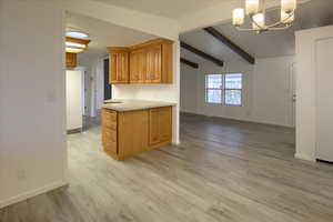 Kitchen featuring vaulted ceiling with beams, a chandelier, light wood-type flooring, and white refrigerator