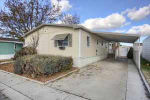 View of front of home with a carport and a storage shed