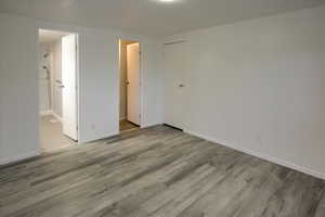 Unfurnished bedroom featuring connected bathroom, light hardwood / wood-style flooring, and a closet