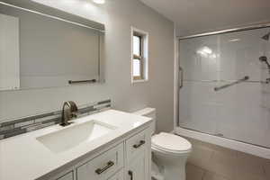 Bathroom with vanity, tile patterned floors, decorative backsplash, toilet, and walk in shower