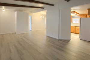 Unfurnished room with vaulted ceiling with beams, light hardwood / wood-style flooring, and a chandelier