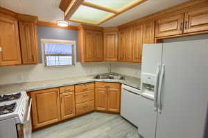 Kitchen featuring sink, white appliances, and light hardwood / wood-style flooring