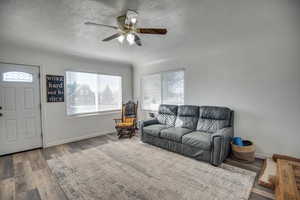 Living room featuring hardwood / wood-style flooring, ceiling fan, and a textured ceiling