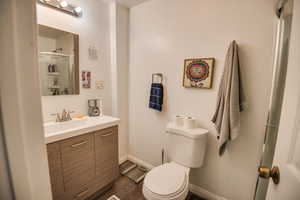 Bathroom featuring hardwood / wood-style floors, vanity, toilet, and a shower with door