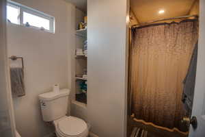 Bathroom featuring a shower with shower curtain and toilet