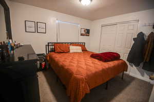 Bedroom featuring carpet flooring, a textured ceiling, and a closet