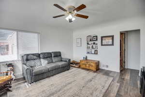 Living room featuring ceiling fan, hardwood / wood-style floors, and a textured ceiling