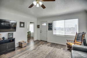 Entrance foyer with wood-type flooring, a textured ceiling, plenty of natural light, and ceiling fan