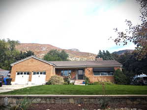 Ranch-style house with a mountain view, a front yard, and a garage