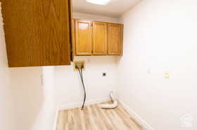 Clothes washing area featuring cabinets, light wood-type flooring, and hookup for a washing machine